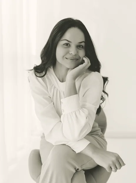 Retrato da psicóloga Mayara Fernanda sentada, com a mão no rosto, em seu ambiente de trabalho em Cascavel